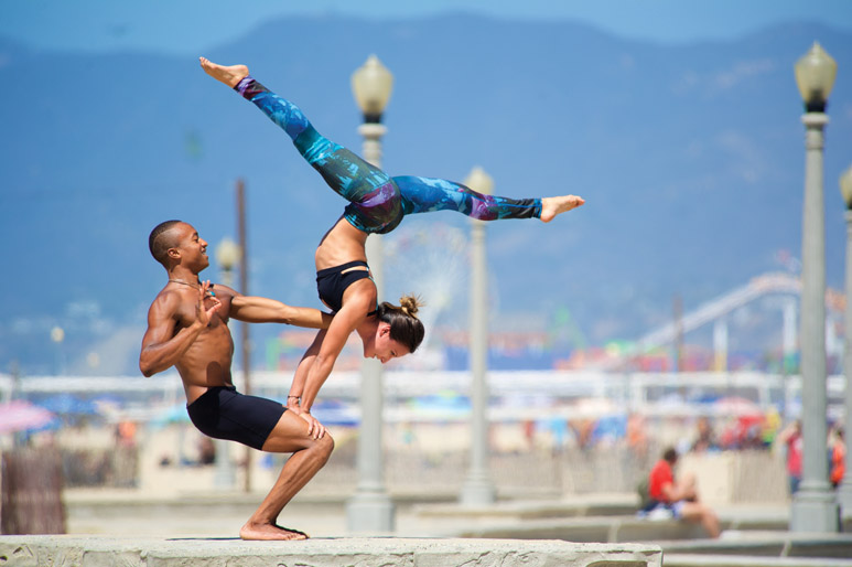 Andrew Sealy and Jen Escare practicing AcroYoga at the beach. 