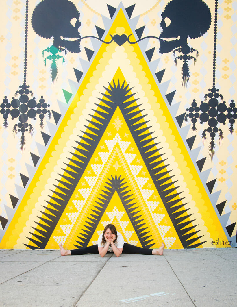 Jessica Rosen in a yoga pose next to an outdoor mural 