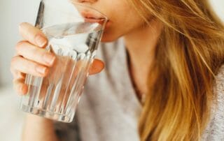 Woman drinking water to receive greater massage benefits