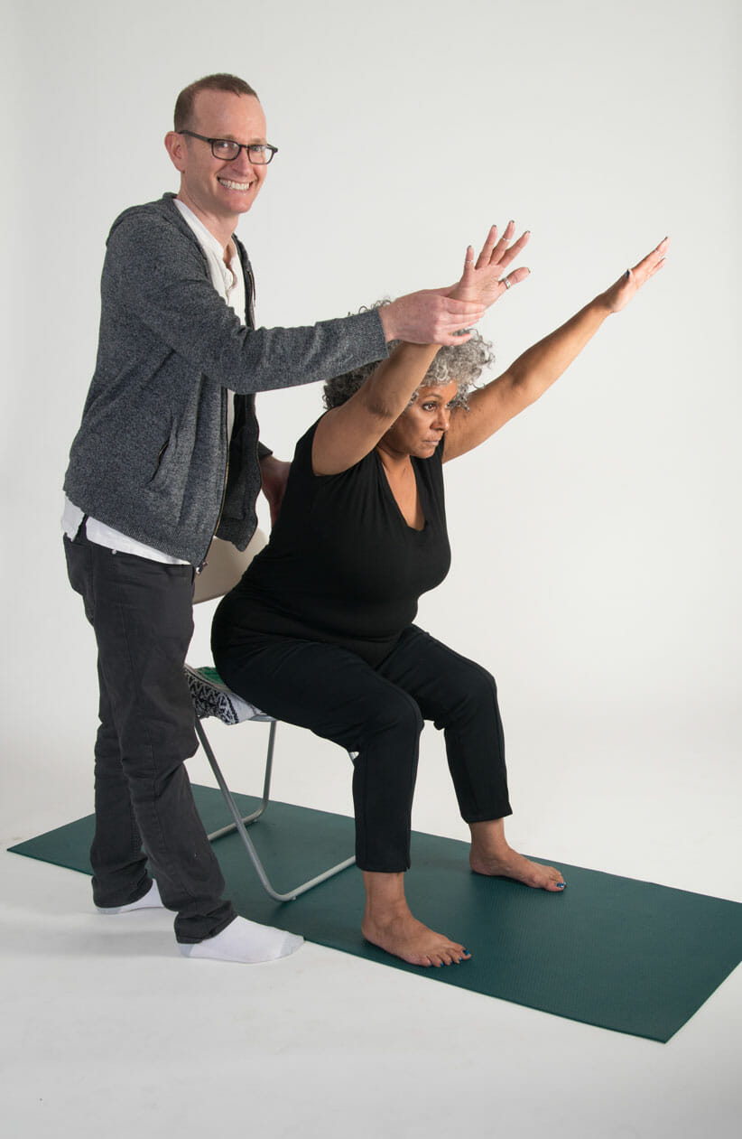 Article Author Jivana Heyman adjusting student in a yoga pose for What Is Yoga 