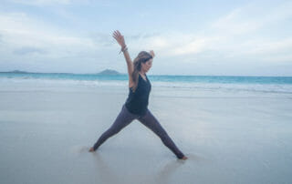 Desi Barlett in yoga pose on the beach demonstrating lessons of yoga