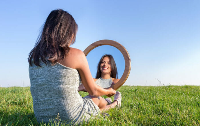 woman looking in mirror to leave the past behind