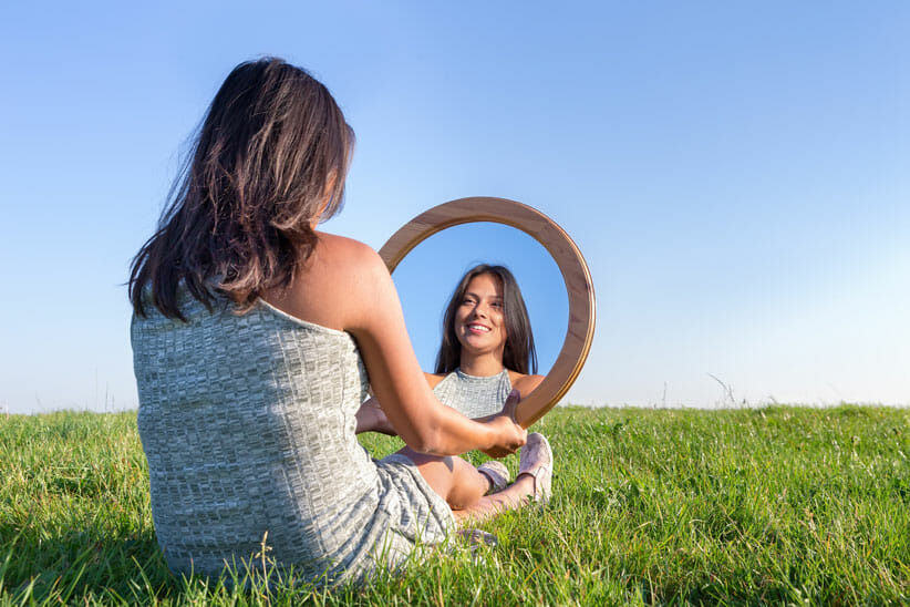woman looking in mirror to leave the past behind