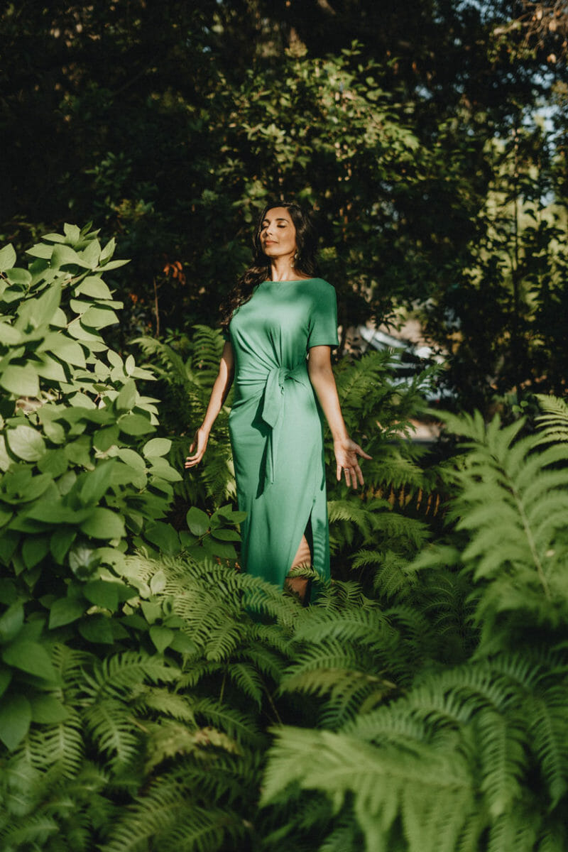Zabie Yamasaki wearing a green dress in the forest with eyes closed