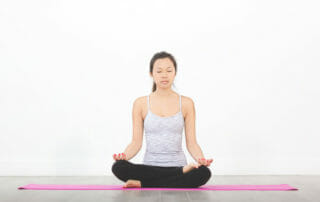 Woman on pink yoga mat in meditation pose set up to deepen your practice