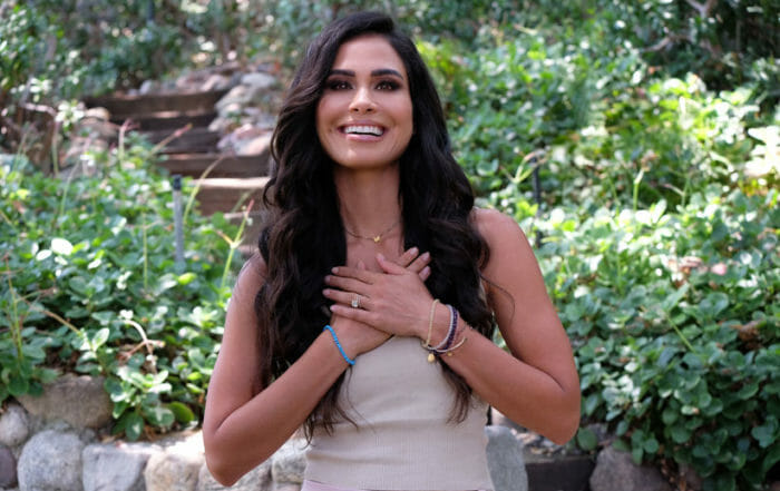 Kimberly Snyder portrait of woman with hands on heart in front of greenery
