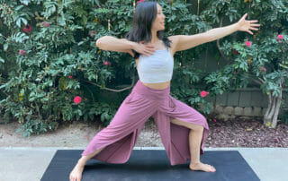Warrior two pose practiced by woman in yoga clothes on mat