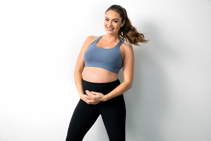 Emily Skye Pregnant Woman holding belly working out while pregnant