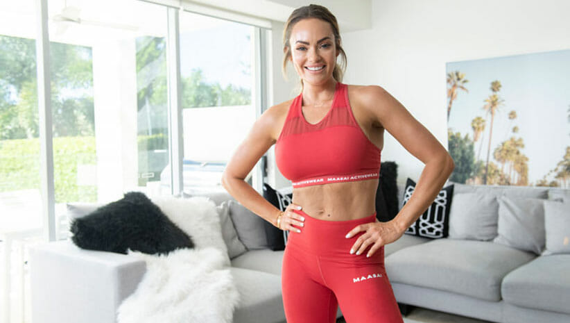 Emily Skye wearing red yoga gear in a spacious room demonstrating exercise routine while traveling