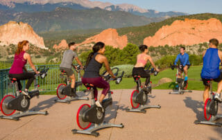 outdoor stationary cyclists at Garden of the Gods with mountains in background