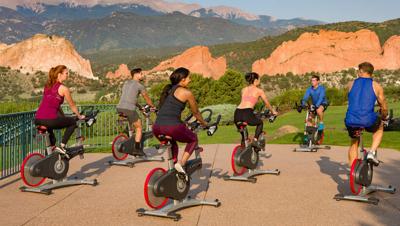 outdoor stationary cyclists at Garden of the Gods with mountains in background