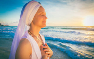 Snatam Kaur by the ocean with hands on heart