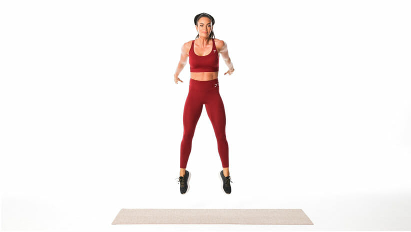 woman demonstrating squat jumps wearing red yoga clothing