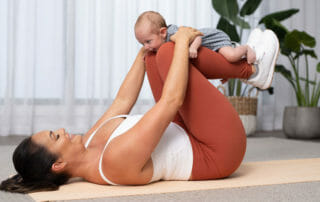woman with baby on legs on yoga mat
