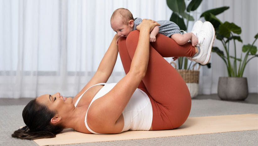 woman with baby on legs on yoga mat