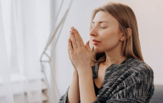 woman with hands in prayer position in front of face for healthy transitions