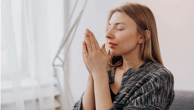woman with hands in prayer position in front of face for healthy transitions