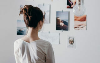 woman gazing at photos on wall representing how to create a vision board