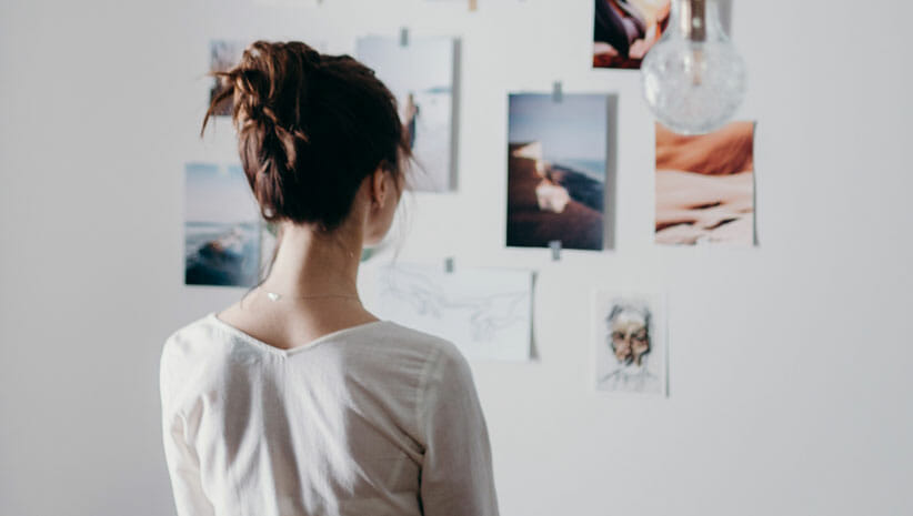 woman gazing at photos on wall representing how to create a vision board