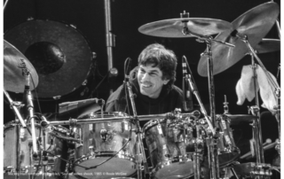 Mickey Hart at drum kit smiling, drums