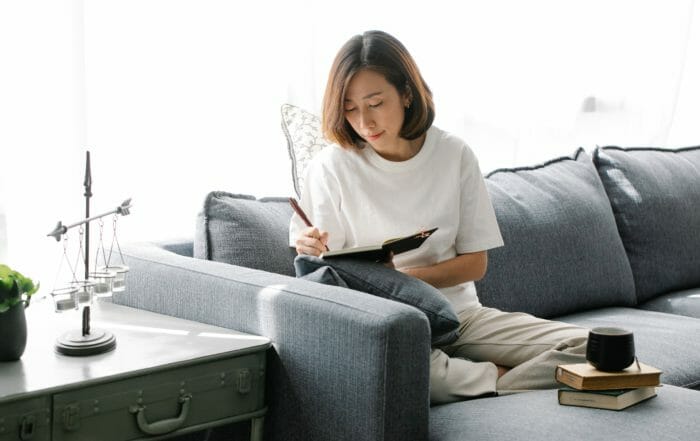 woman on couch writing in journal writing affirmations that work