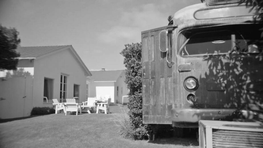 Black and white photo lawn, white chairs and old bus
