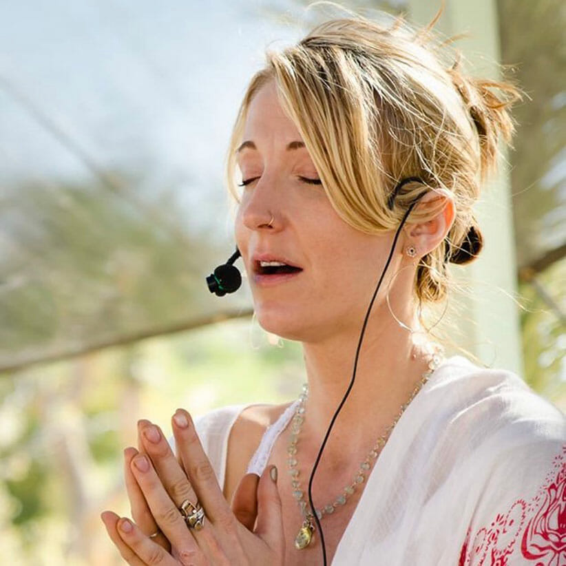 Johanna Beekman with microphone and hands in prayer pose