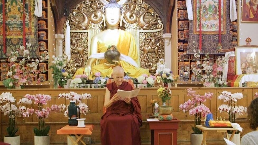Buddhist Nun in red monastic dress at altar