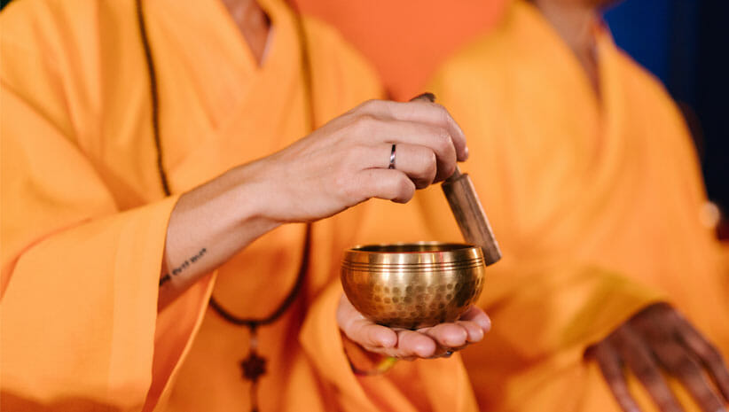 monk in orange holding singing bowl