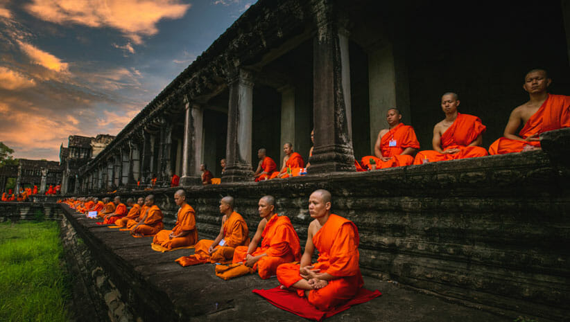 Row of monks in orange on temple steps
