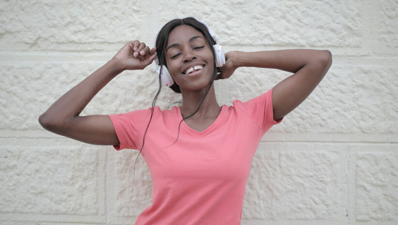 woman with dark skin and pink shirt with headphones on