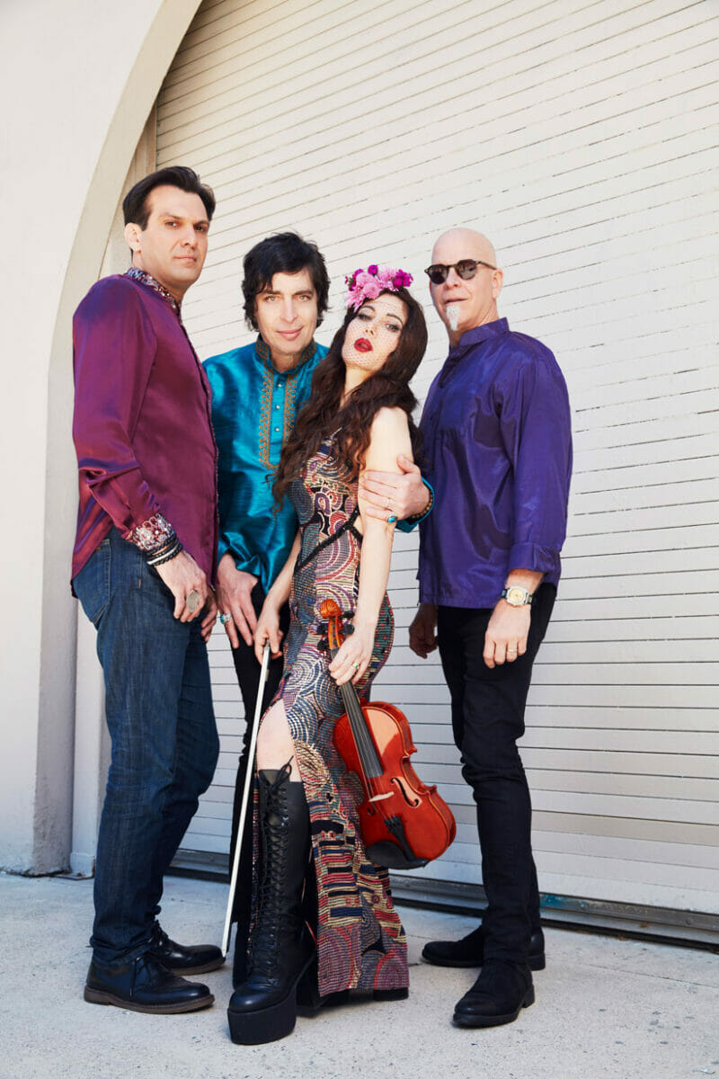 members of band Opium Moon standing in front of a wall. Lili Haydn holding violin