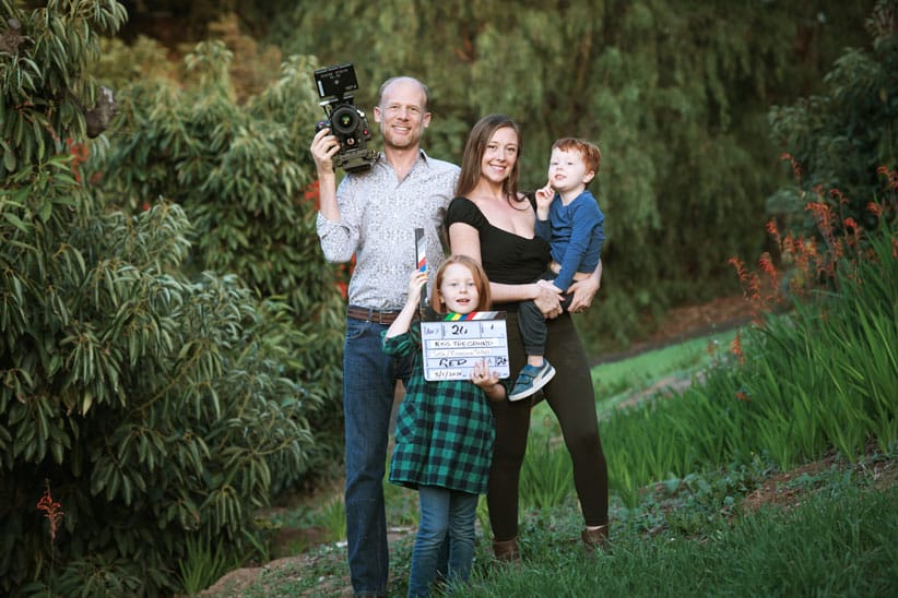 Tickell family holding filmmaking equipment standing in front of trees.