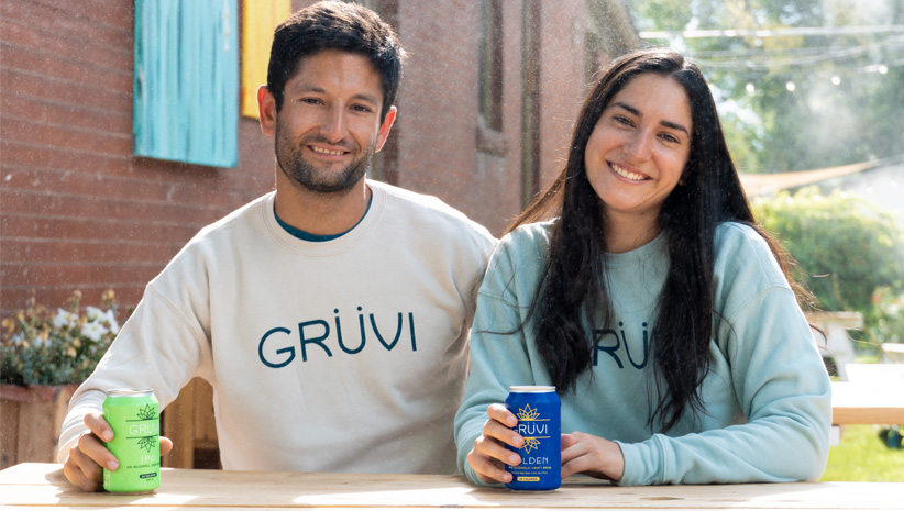 man and woman wearing casual clothes from Grove holding non-alcoholic beverages and smiling