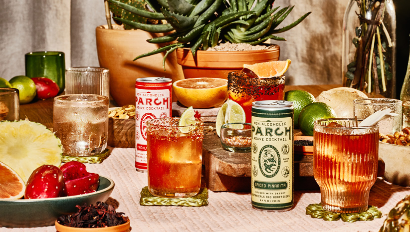 PARCH non-alcoholic drinks in cans with drink in glass and foliage on table