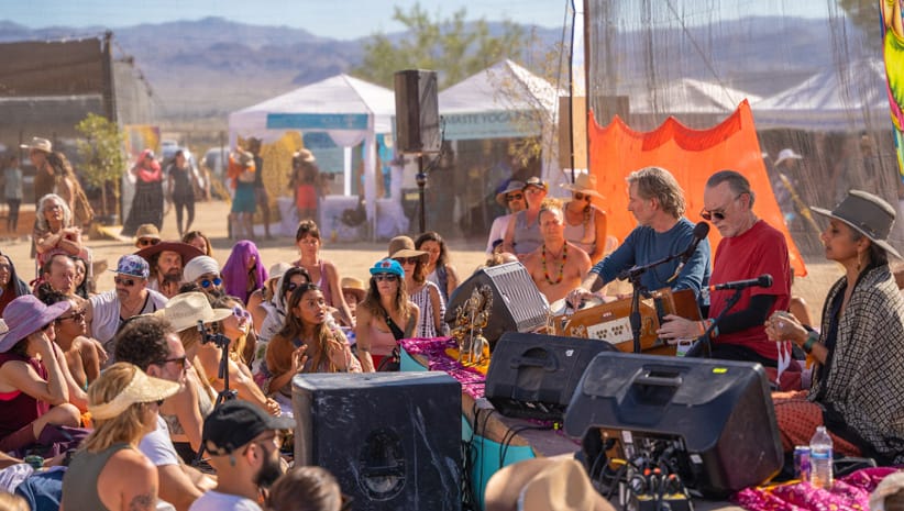 Kirtan artist Krishna Das in front of a stage and crowd of people. 