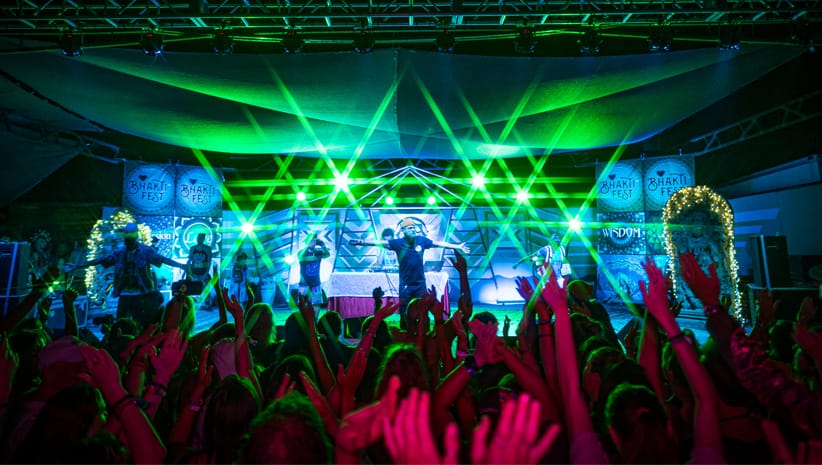 Green lights shining on Bhakti Fest stage with musicians leading the crowd.