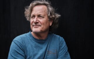 Photo of filmmaker and teacher Stacy Peralta wearing a blue shirt and looking off into the distance