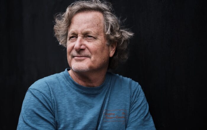Photo of filmmaker and teacher Stacy Peralta wearing a blue shirt and looking off into the distance