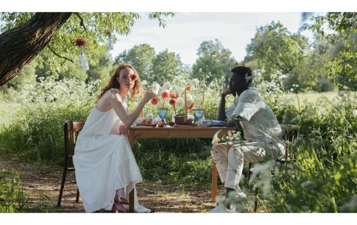 Two people sitting at a picnic table in the midst of a field of flowers for summer picnics